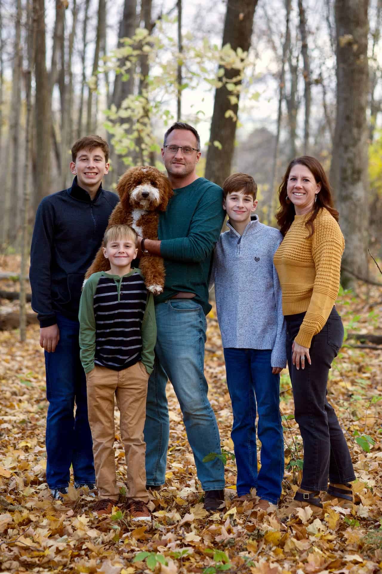 Family portrait of 3 boys in the woods with a puppy