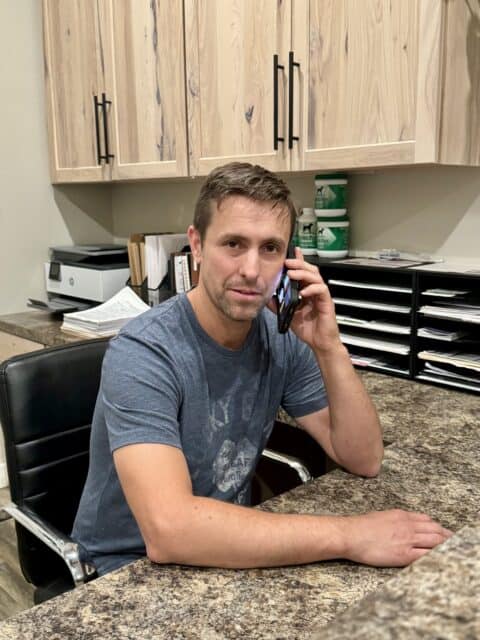 Robin talking to puppy owner on the phone at his home office