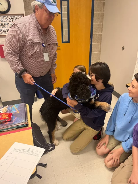 Trained therapy Bernedoodle hugging child