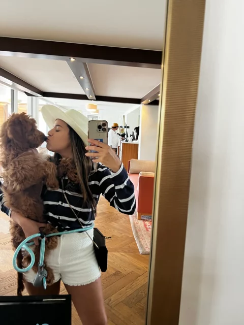 Woman taking a selfie kissing her Goldendoodle puppy on the nose