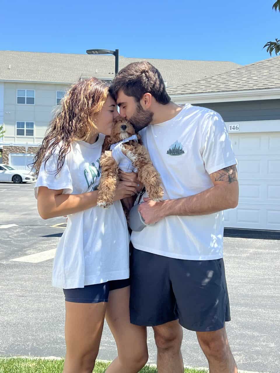 Young couple kissing their new Goldendoodle puppy